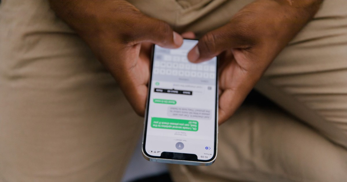 Close-up view of hands texting on a smartphone, focusing on the screen displaying messages.