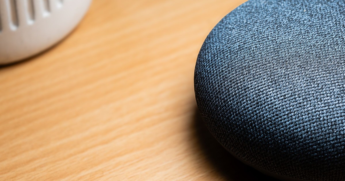 A close-up view of a smart speaker on a wooden table, capturing texture details.