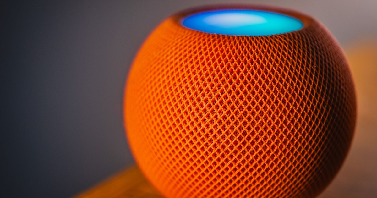 Close-up of an orange smart speaker with a glowing blue light, showcasing modern technology.