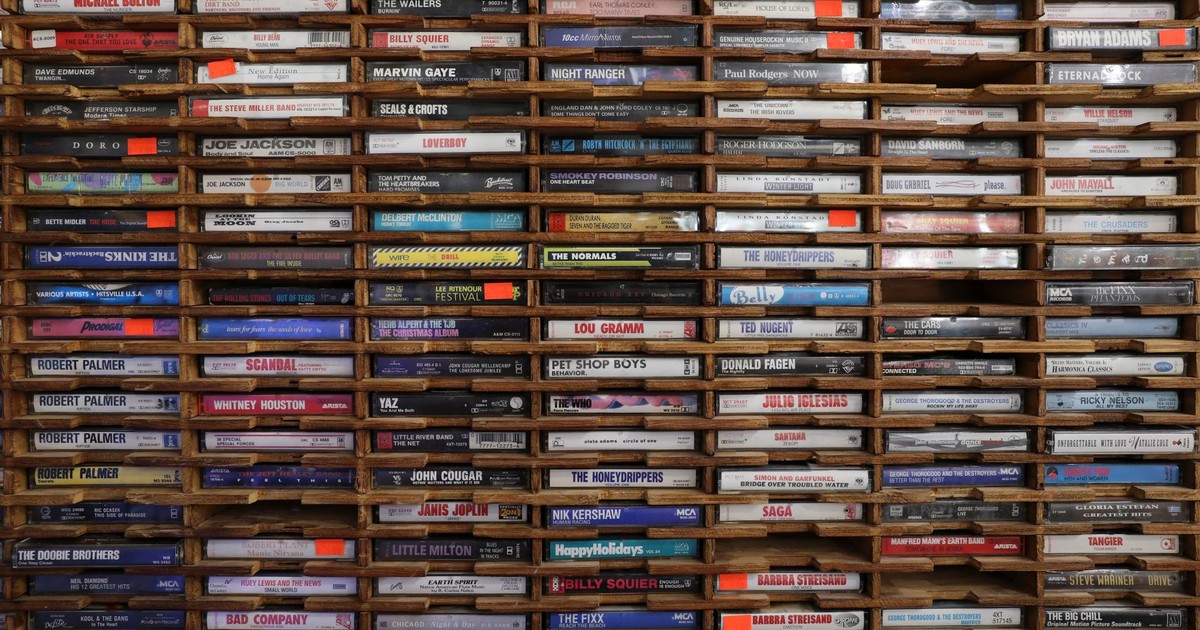 A large collection of vintage cassette tapes neatly organized on wooden shelves.