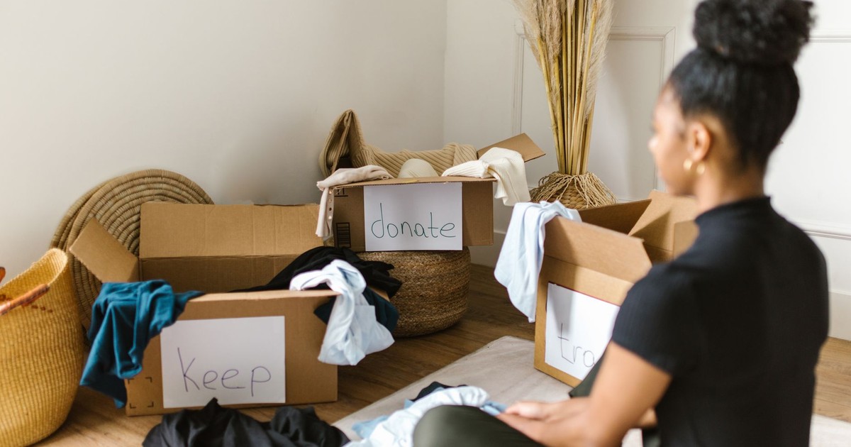 A woman organizing clothes into labeled boxes for donation and keeping.