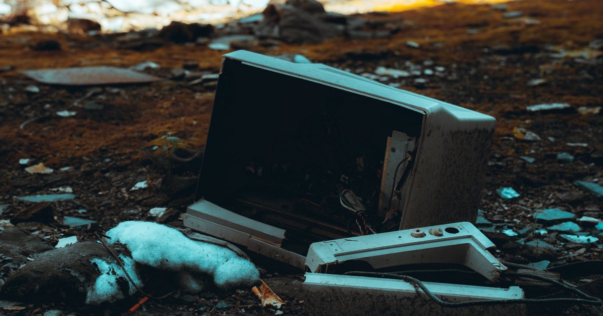 Broken TV screen in an abandoned, desolate urban environment amidst debris and wreckage.