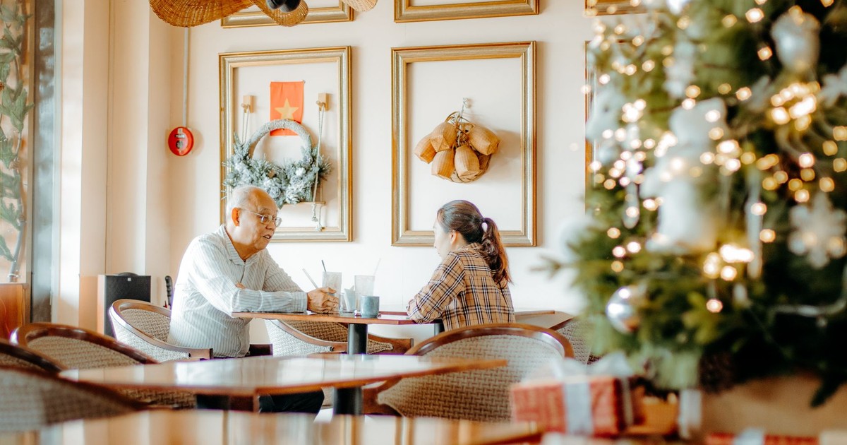 A festive cafe setting with two people discussing over drinks, surrounded by Christmas decor.