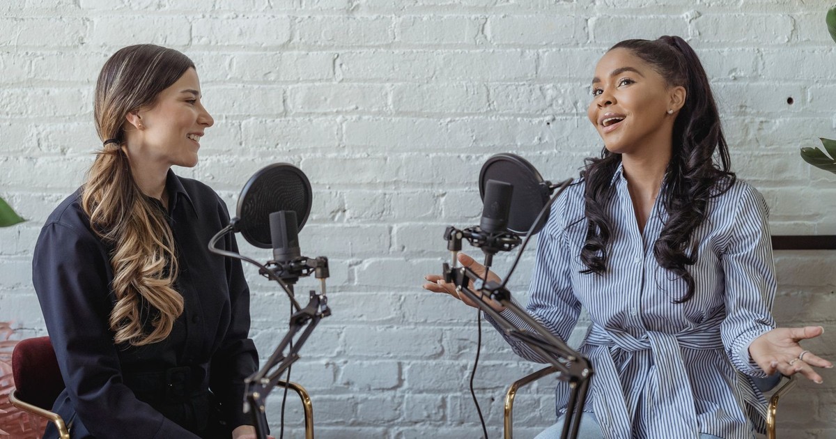 Smiling African American female guest gesticulating while having interview with journalist sitting near mic