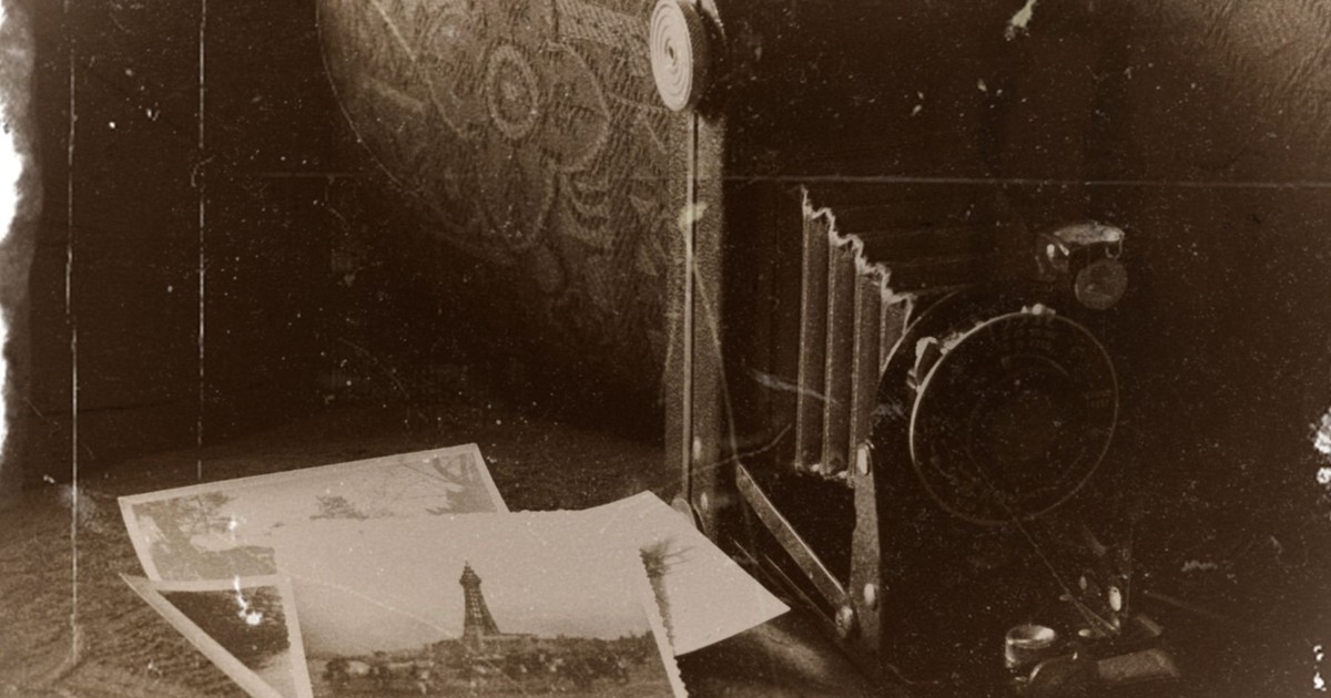 Sepia-toned image of a vintage camera with old photographs, capturing nostalgic memories.