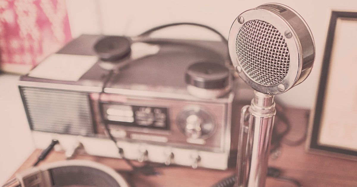A classic vintage microphone and radio set with headphones displayed on a wooden table.