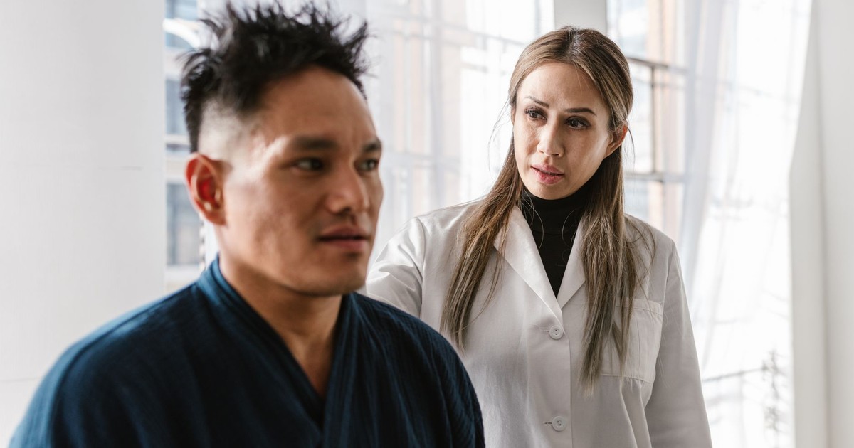 A medical practitioner attentively consulting a patient in a bright indoor clinic setting.