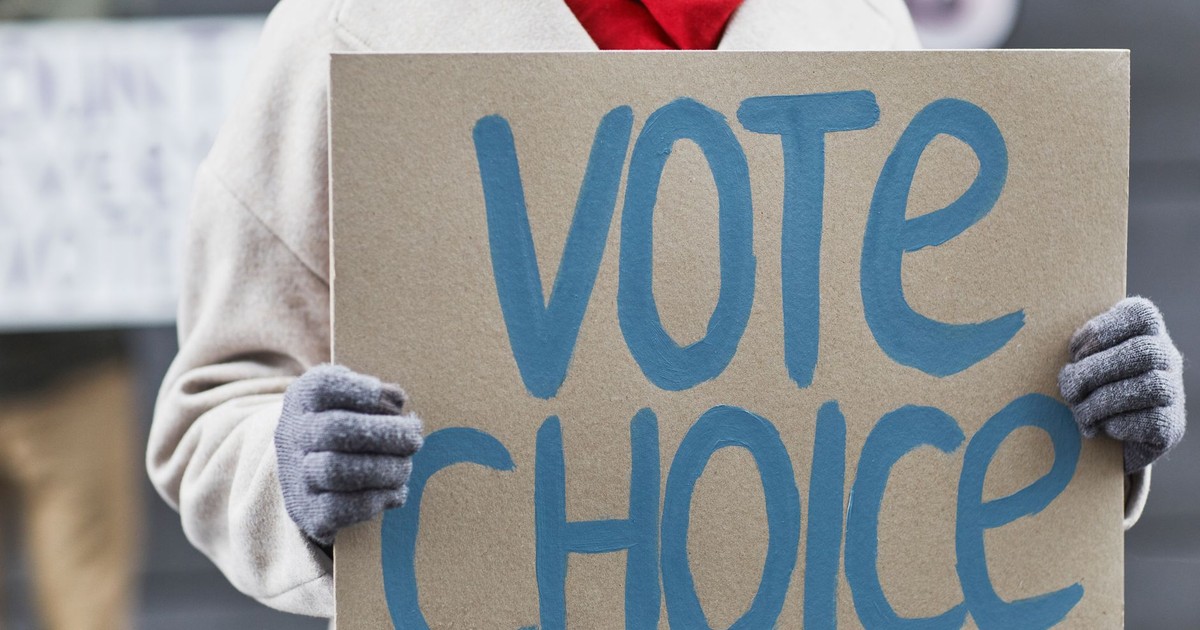 Close-up of a person holding a Vote Choice sign during a protest outdoors.