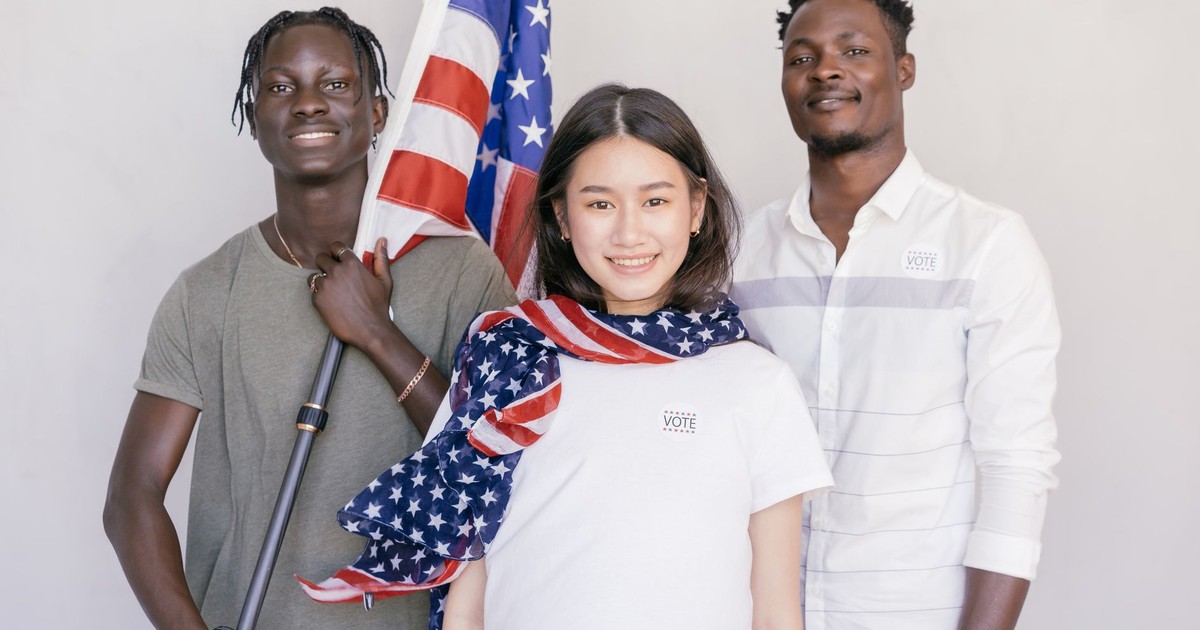 A diverse group of young adults holding an American flag, promoting voting and civic engagement.