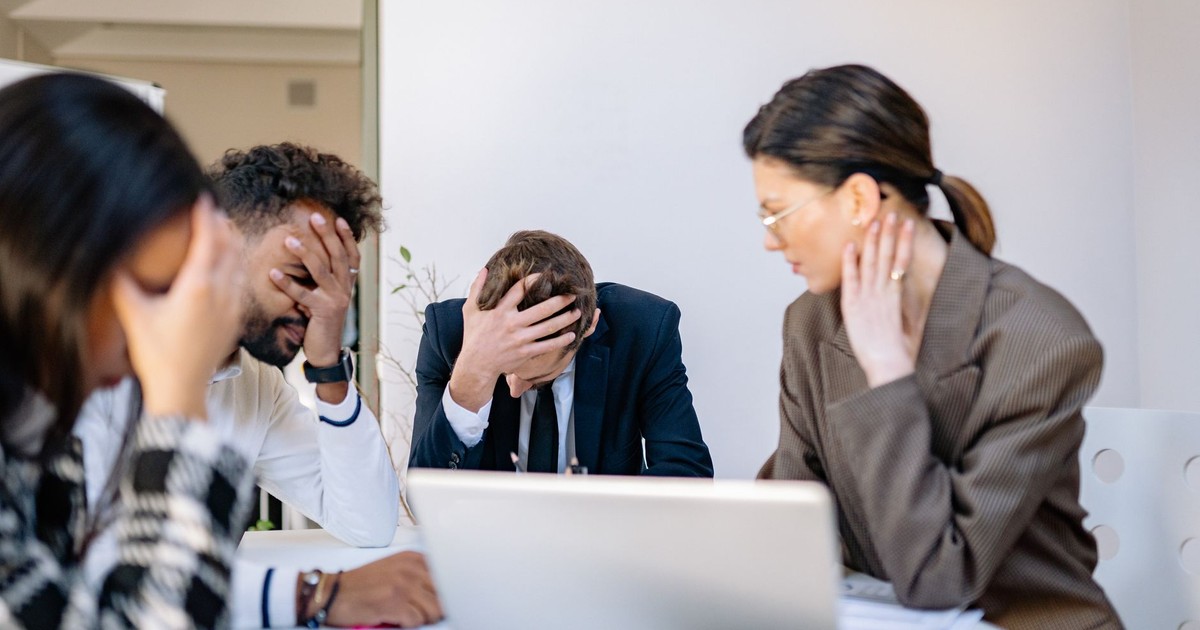 A group of stressed business professionals in an office setting, overwhelmed by work.