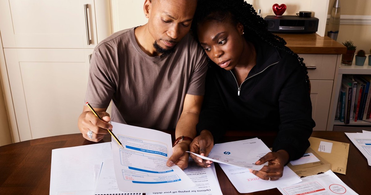A couple sitting at a table reviewing financial documents, highlighting domestic budgeting.