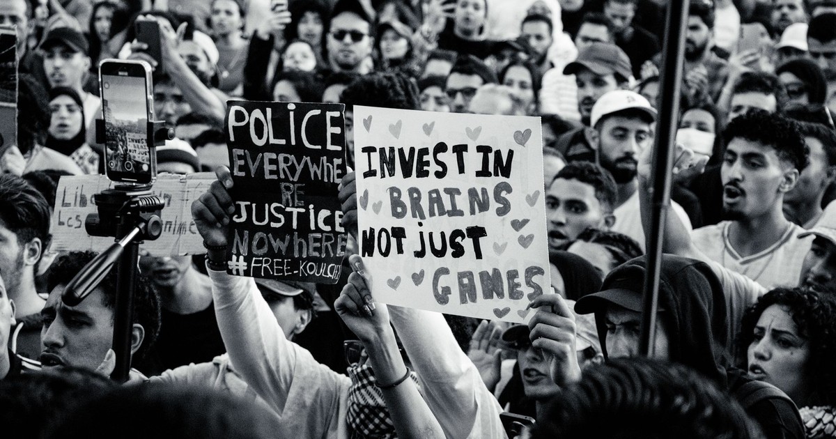 Crowd of young adults protesting with impactful signs in black and white.