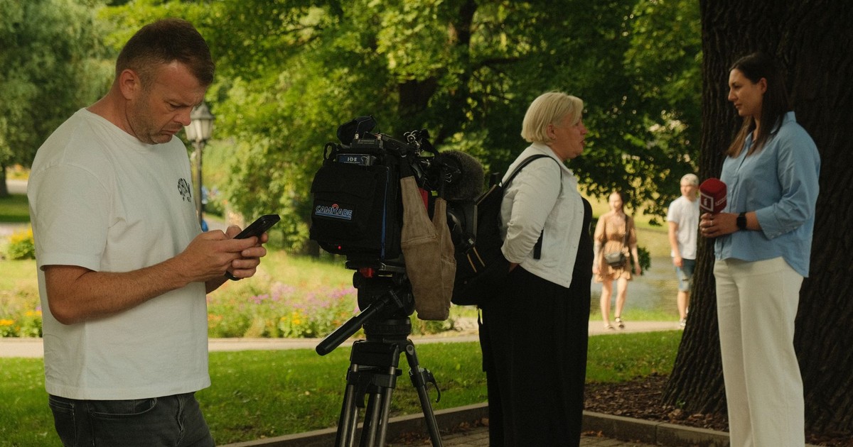 News crew conducting outdoor interview with professional camera setup in a lush park.