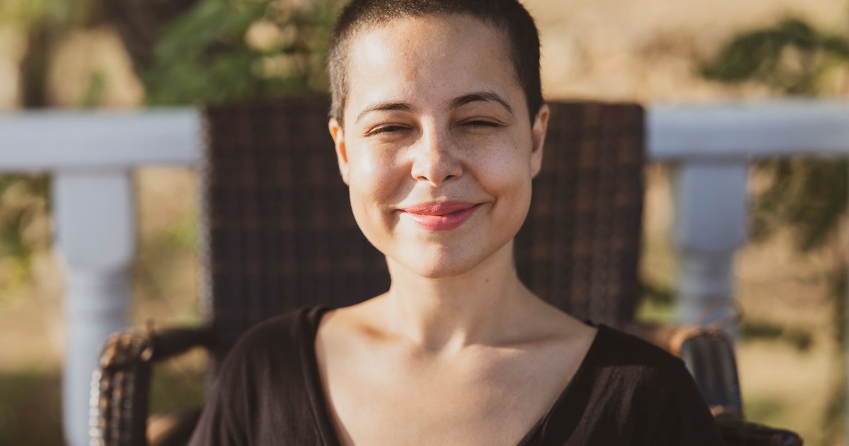 A young woman with a buzz cut enjoys the summer sun, her smile radiating happiness and relaxation.