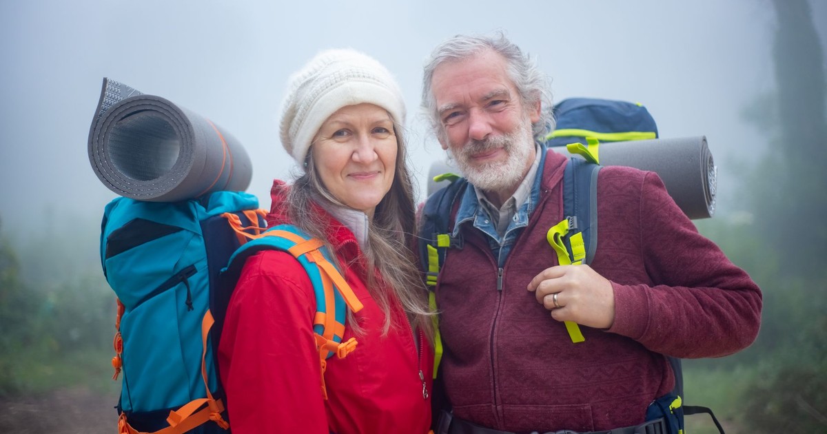 Senior couple hiking together in foggy scenery in Portugal, showcasing adventure and companionship.