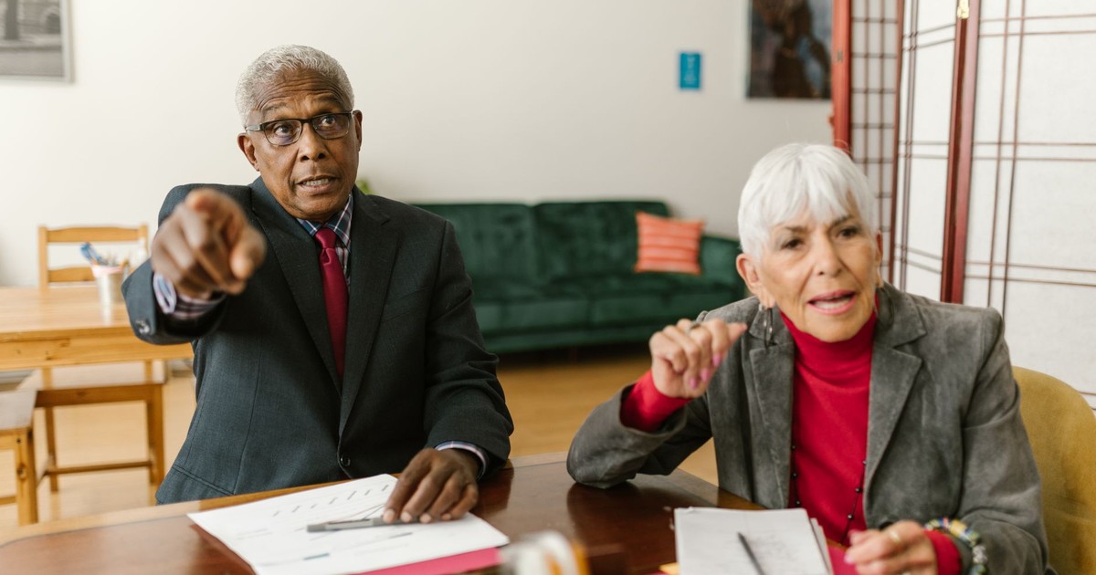 Elderly professionals engaged in an office discussion, emphasizing teamwork and corporate dynamics.