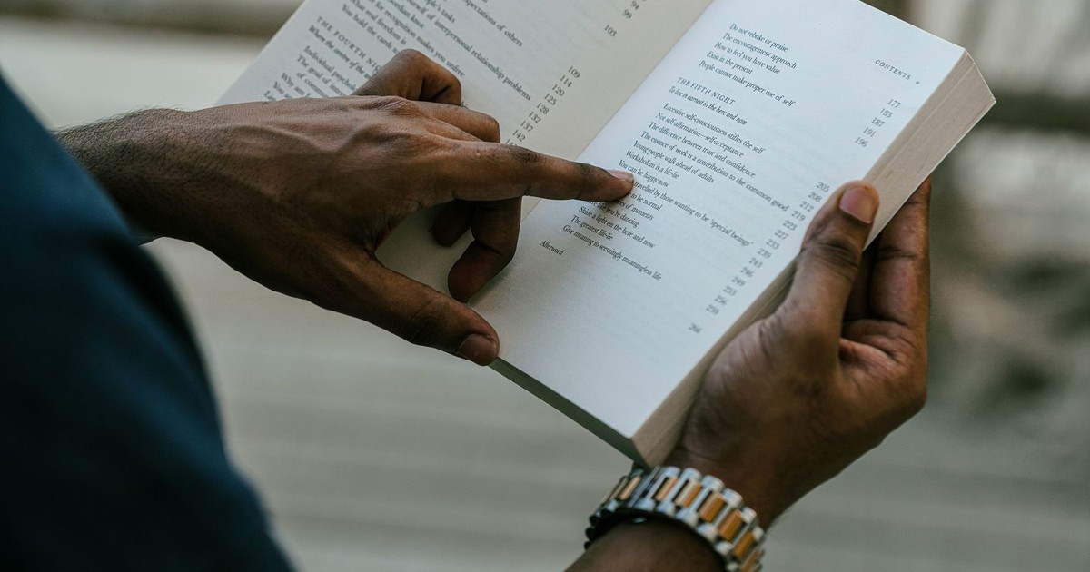 Close-up of a person reading an open book outdoors, capturing focus and inspiration.