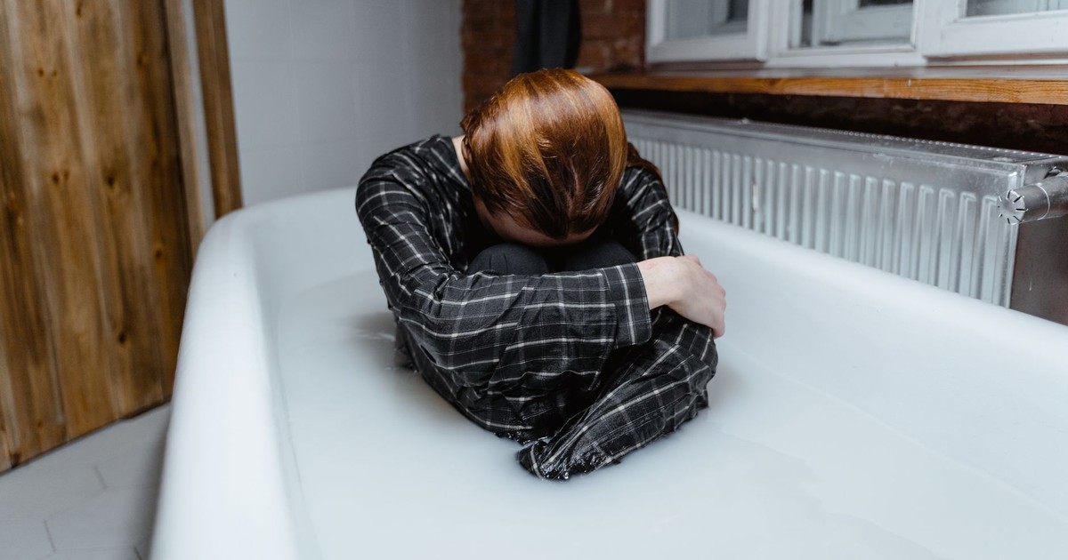 A person in a bathtub showing feelings of sadness and isolation, indoors.