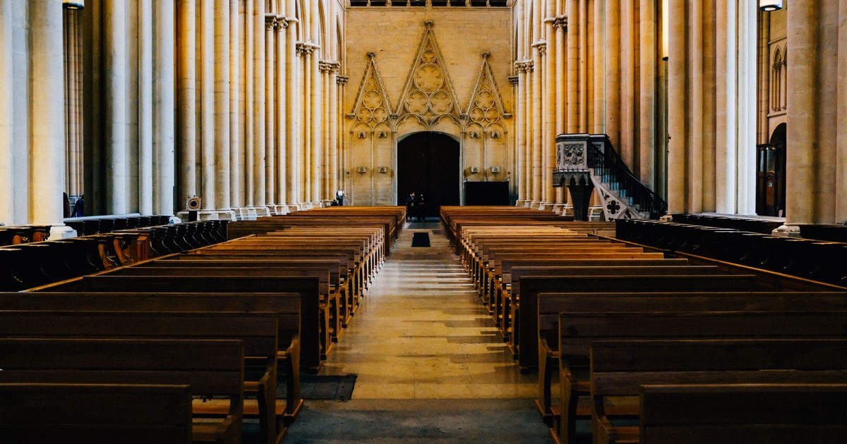 Empty pews in a Gothic cathedral interior, showcasing majestic columns and arches.