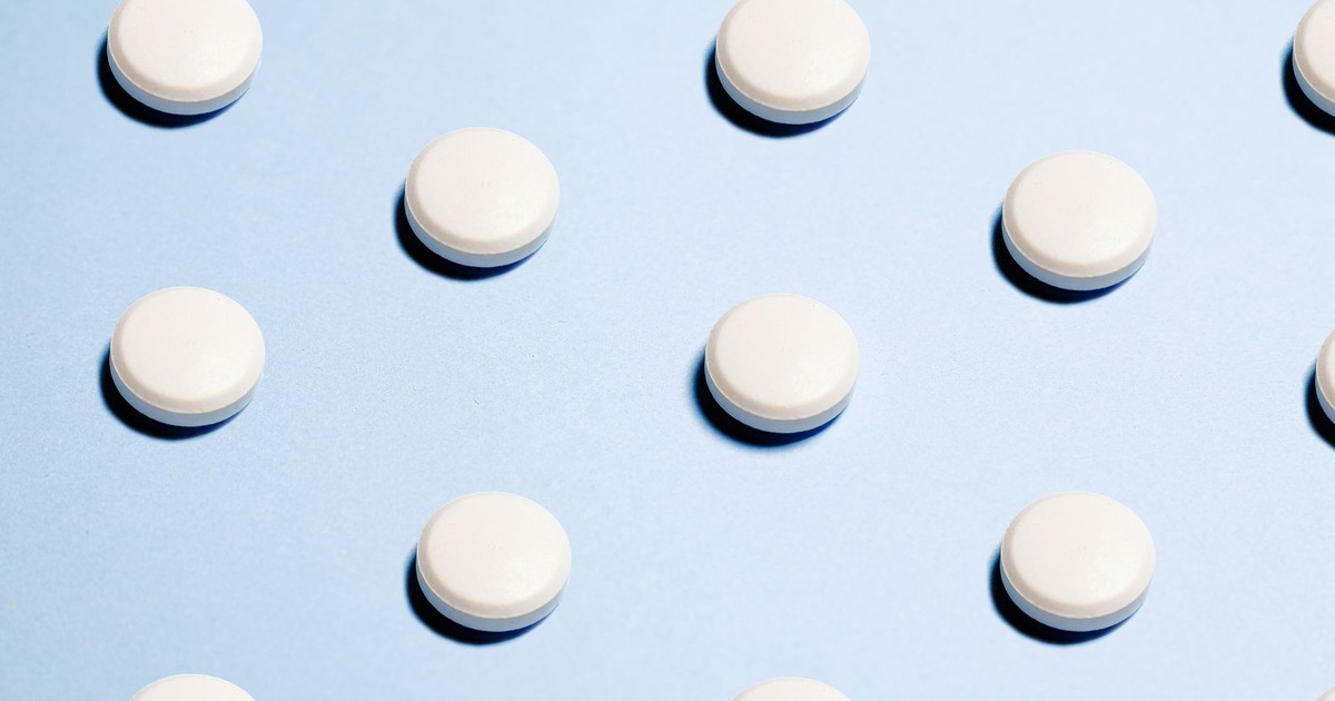 Array of white pills on a light blue background, ideal for healthcare themes.