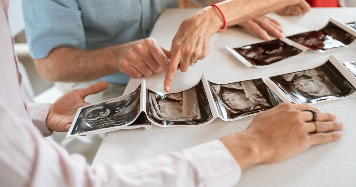 Family members gather around a table to discuss ultrasound photos, symbolizing love and anticipation.