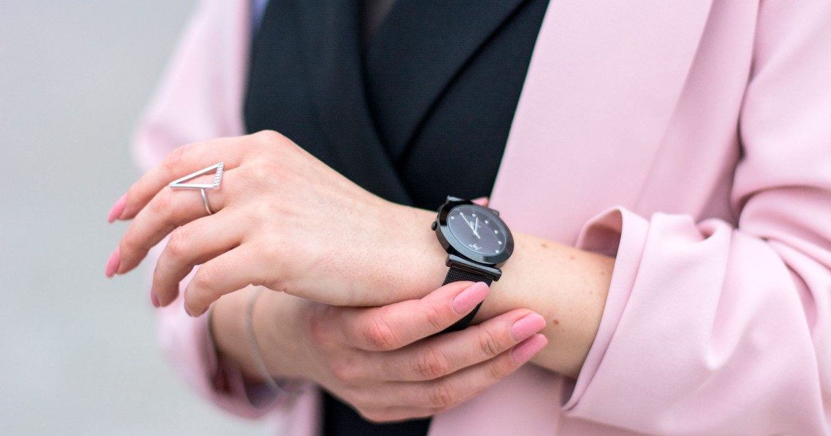 Close-up of a stylish woman adjusting her wristwatch, showcasing elegance and modern fashion.