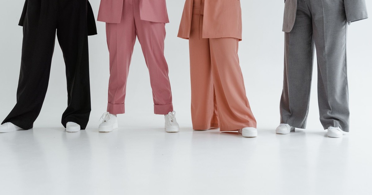 Fashionable women in stylish suits posing indoors on a white background.