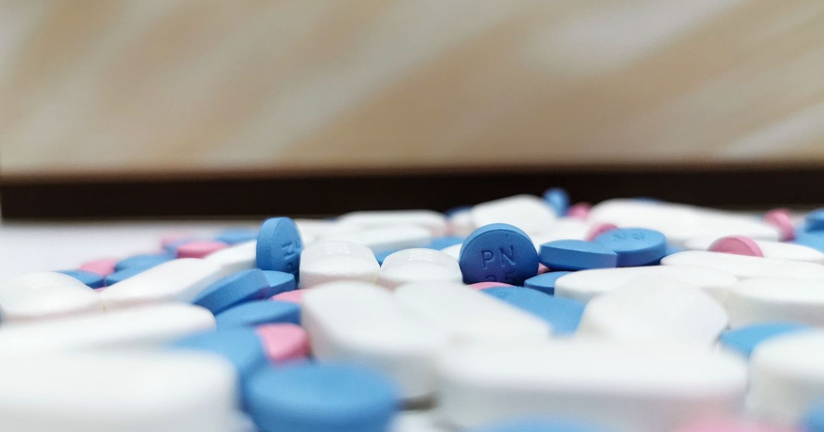 Close-up image of assorted blue and white pills scattered on a table, indoors.