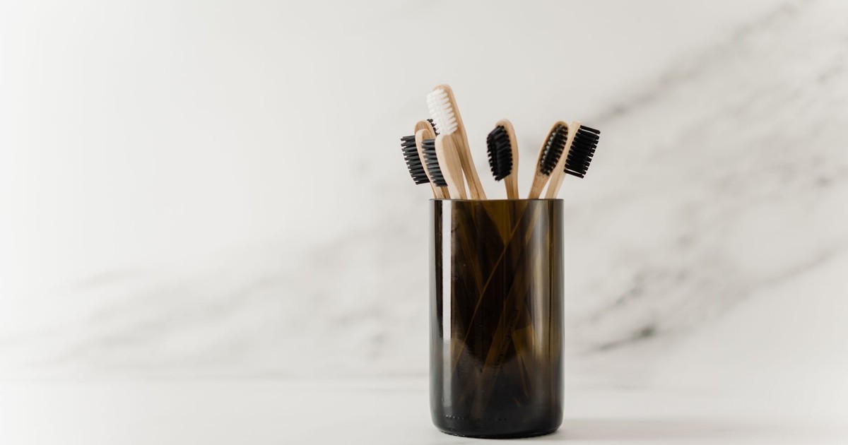 Set of eco-friendly bamboo toothbrushes in a glass holder, showcasing a minimalist design.