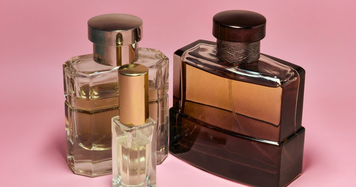 Three stylish perfume bottles with elegant caps on a pink backdrop, capturing a sense of luxury and sophistication.
