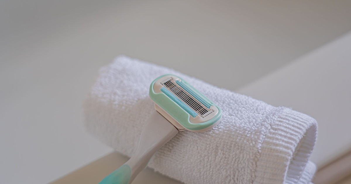 A disposable razor placed on a rolled white towel in a bathroom, highlighting grooming essentials.