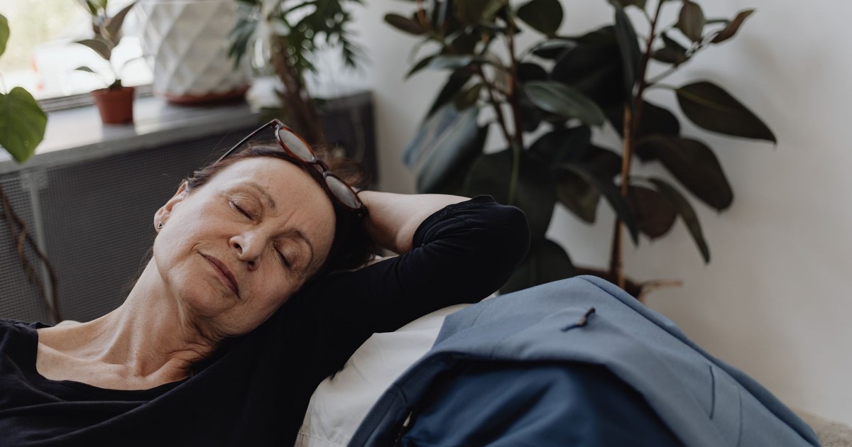 A serene elderly woman relaxing indoors surrounded by houseplants, reflecting peace and calm.