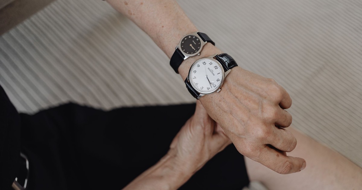 Elderly woman checking time on two wristwatches, symbolizing time management.