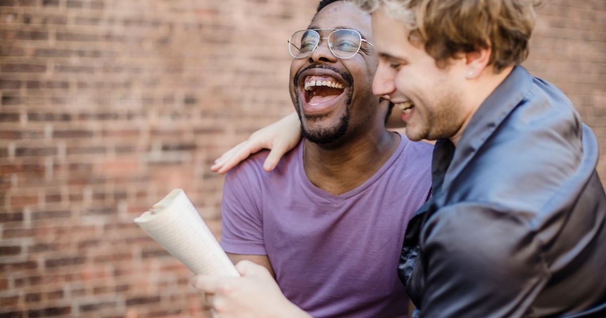 Two happy men in a loving, joyful moment, sharing laughter on a sunny day.