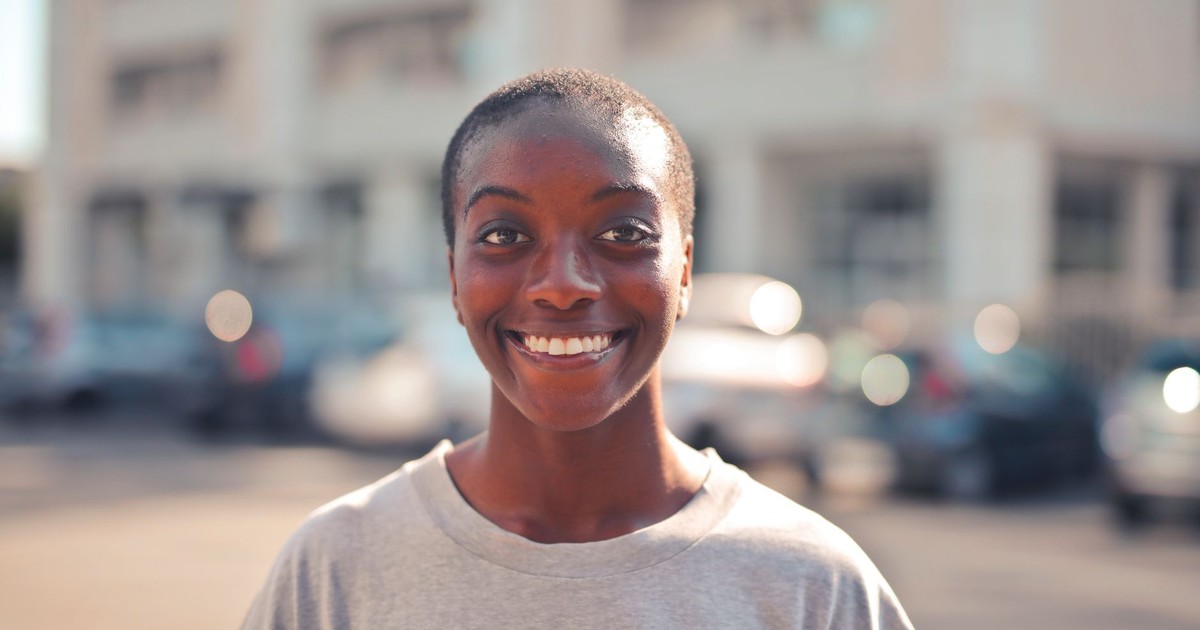 Happy woman smiling outdoors with a soft focus background.
