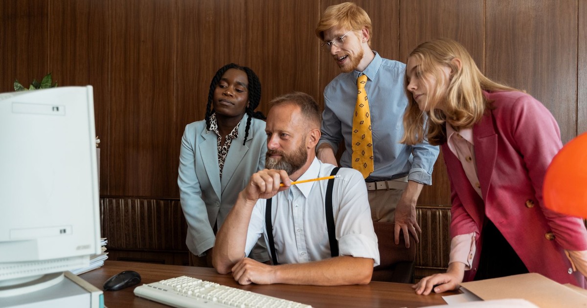 A diverse team of colleagues collaborating at a vintage office desk, engaging with a computer.