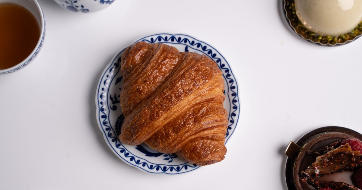Delicious croissant on a decorative plate with coffee, making a classic French breakfast scene.