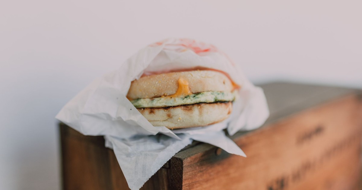 Close-up of a delicious breakfast sandwich with cheese and egg on a wooden box.