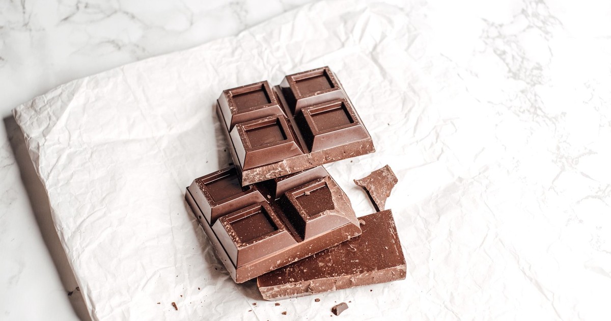 Close-up of dark chocolate bar on crumpled white paper, showcasing texture.