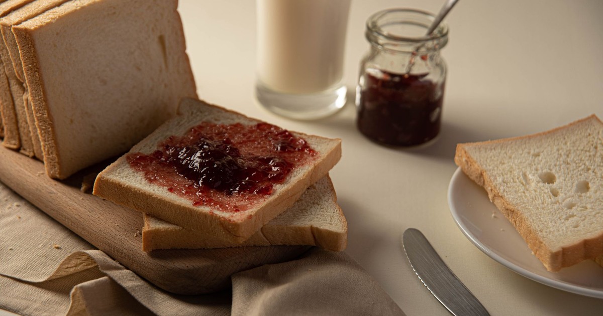 A close-up of sliced bread with strawberry jam and a glass of milk, perfect for breakfast ideas.