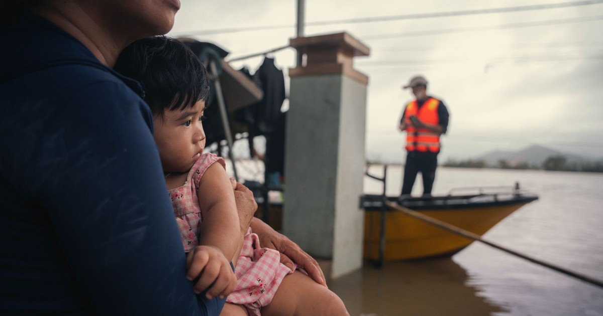 A mother holds her child amid floodwaters in Phú Yên, Vietnam, showcasing resilience and community support.