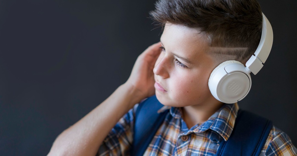 Portrait of a young boy wearing headphones and a plaid shirt, enjoying music.