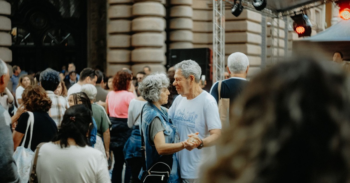 Charming scene of an elderly couple dancing amidst a lively crowd at a street festival.