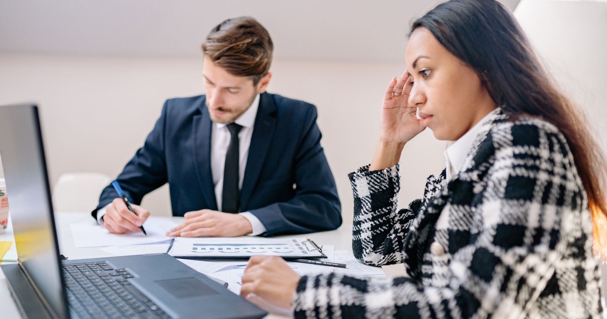 Two business professionals working together in an office, focusing on a project.