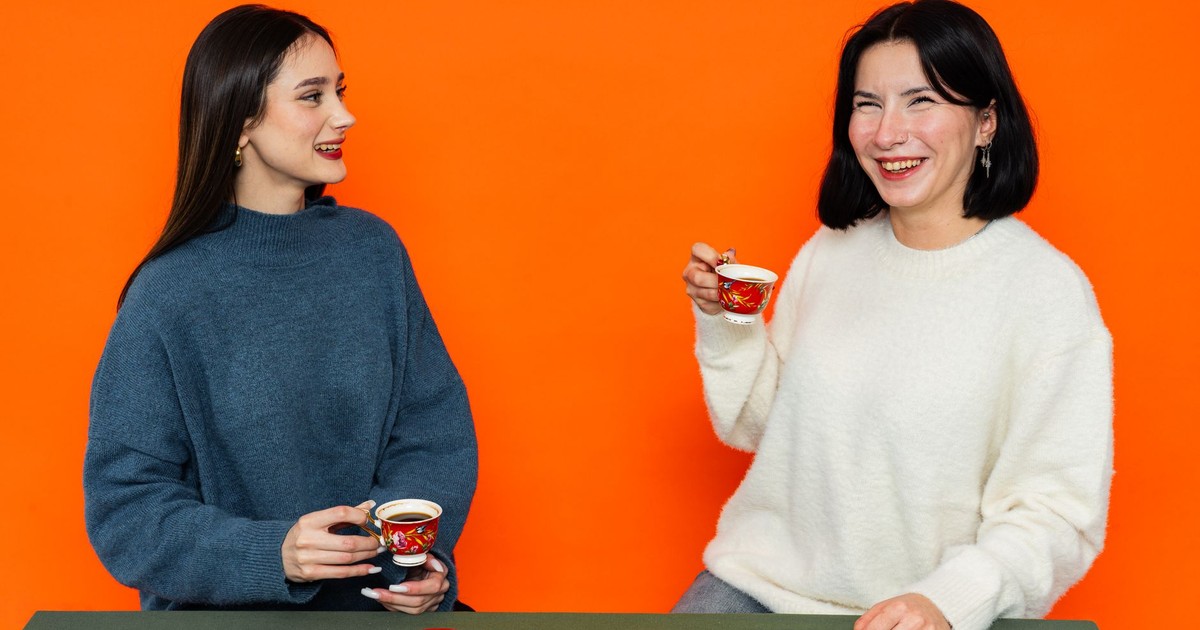 Two women enjoying Turkish coffee in a cozy setting with colorful background.