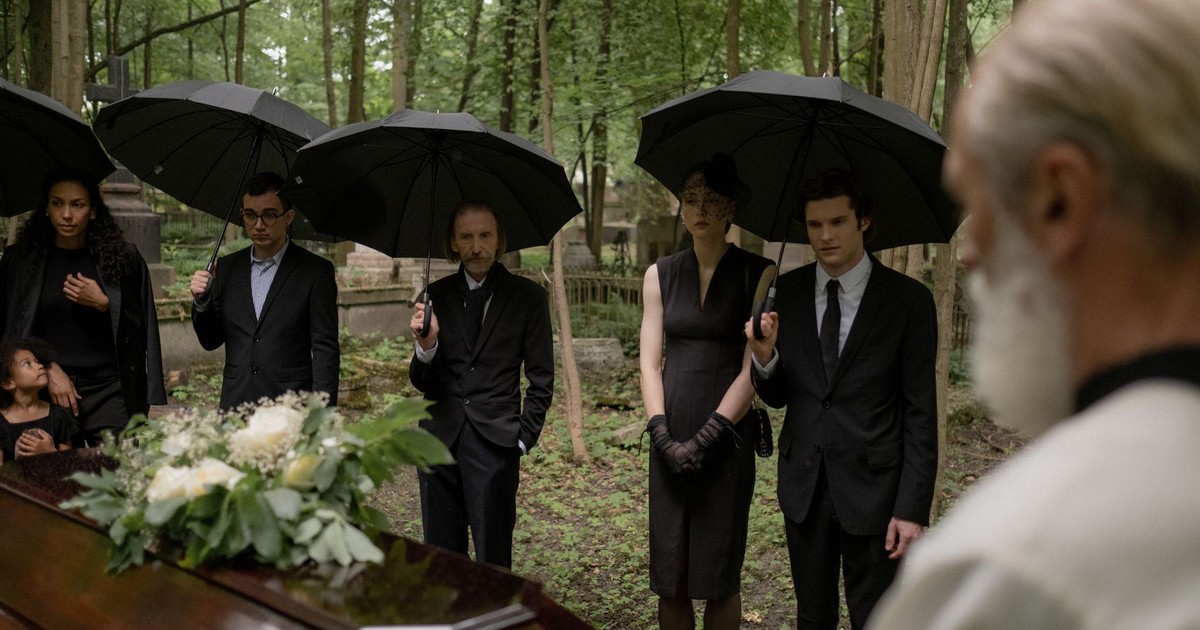 A group mourns during a funeral gathering in a forest cemetery.