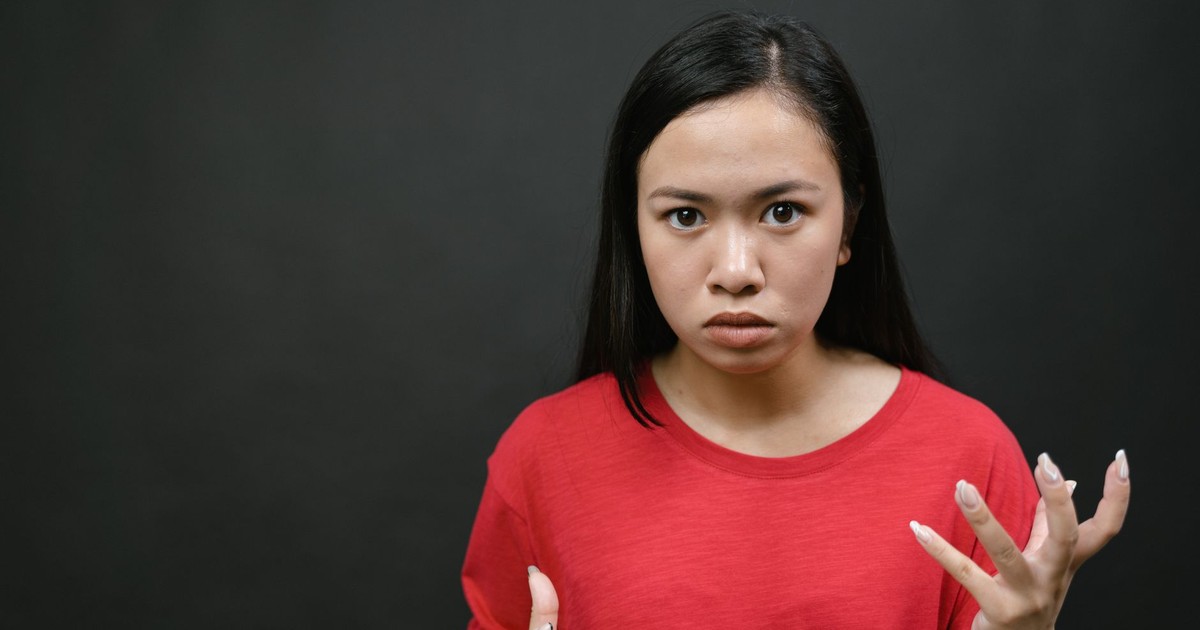 A young woman with expressive hands showing emotions against a dark background.