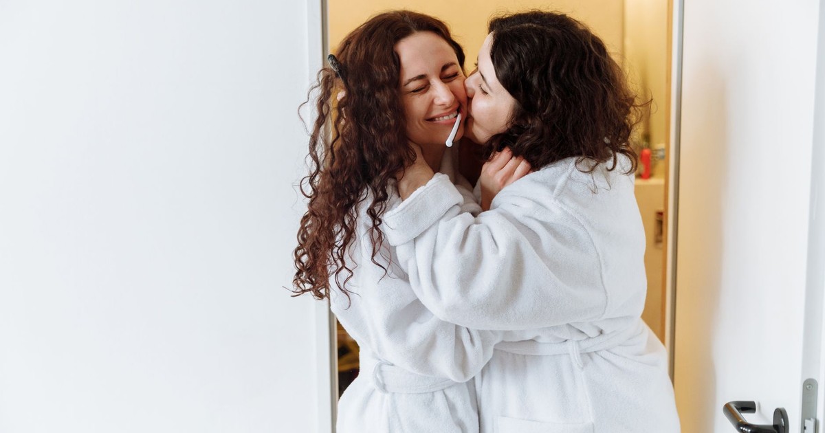 A loving couple in white bathrobes embracing and sharing a tender moment indoors.