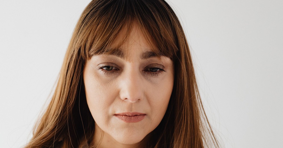 Close-up of a thoughtful woman with long hair, captured indoors, conveying a pensive mood.