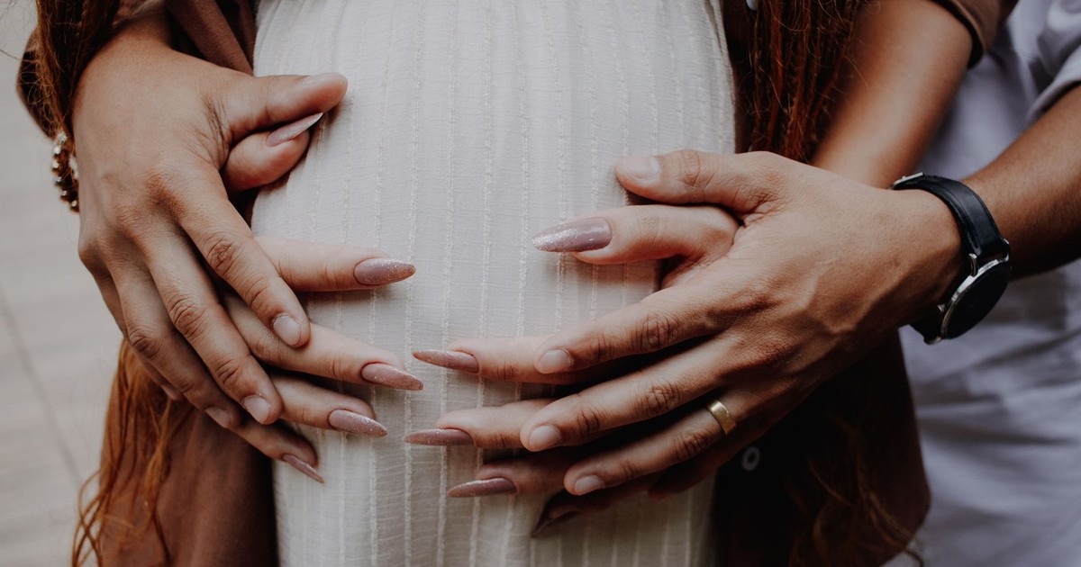 Intimate close-up of hands embracing a pregnant belly, symbolizing love and family bonds.